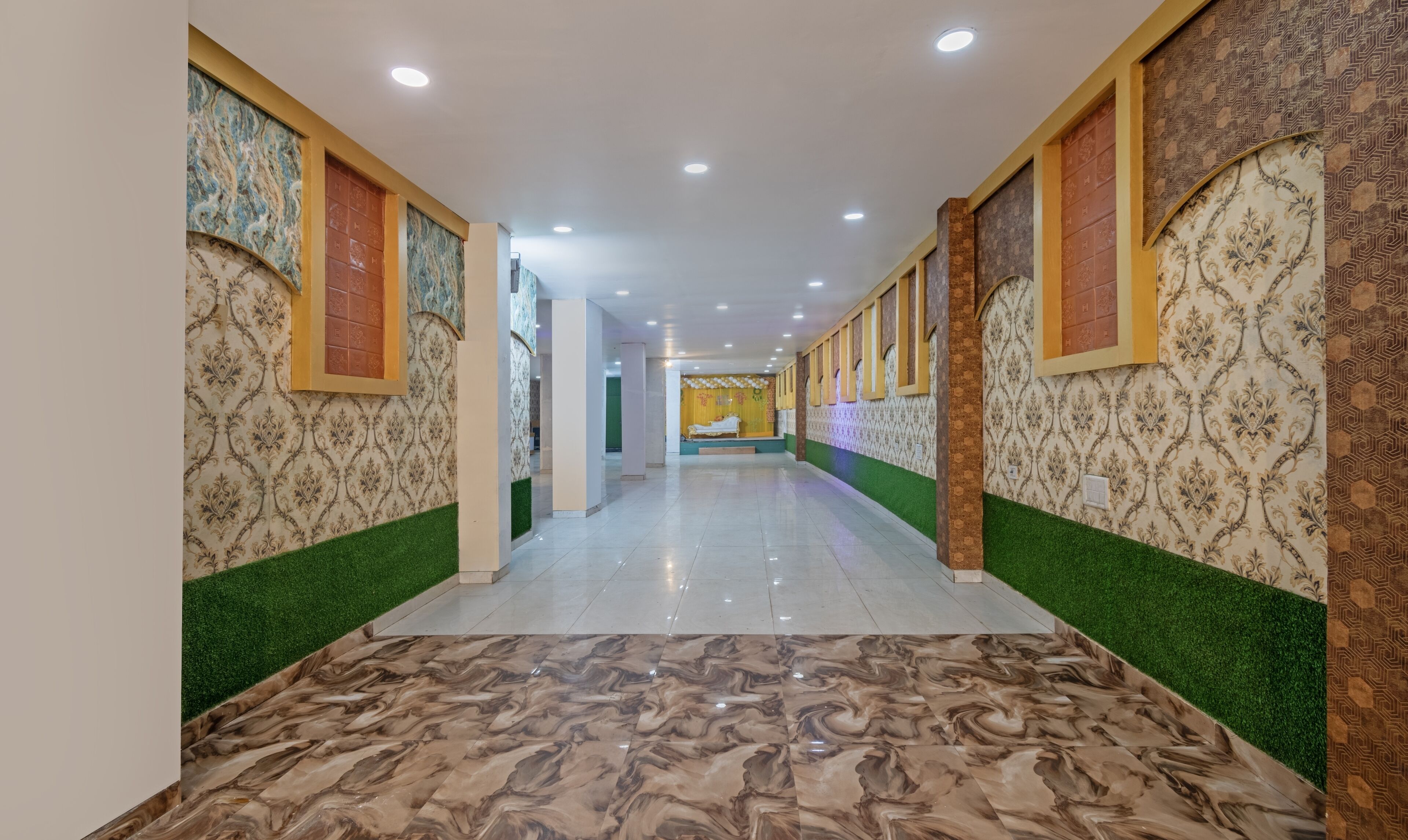 Corredor com papel de parede estampado, grama sintética verde e piso de mármore.