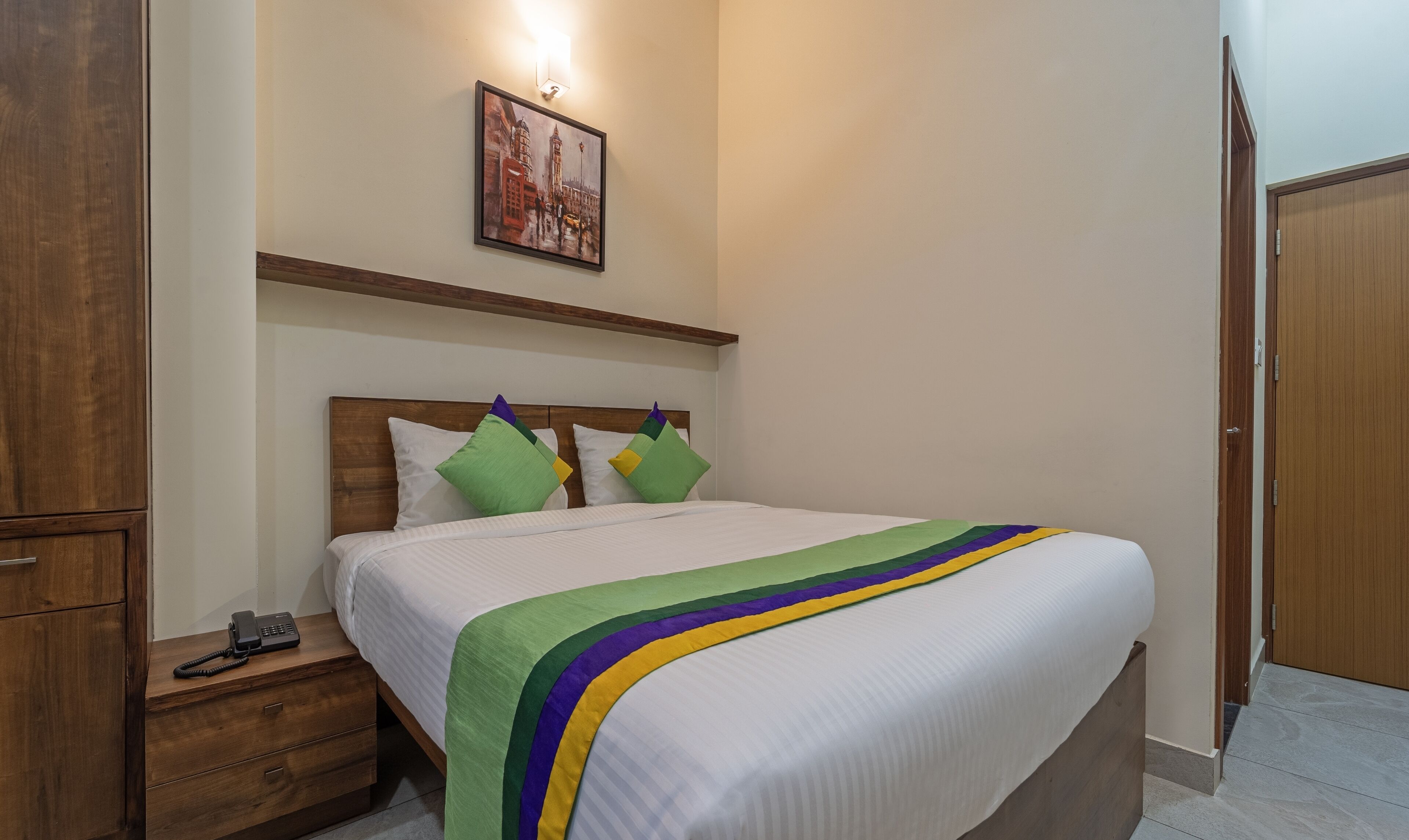 Une chambre d’hôtel avec un lit, une table de chevet en bois et un téléphone.