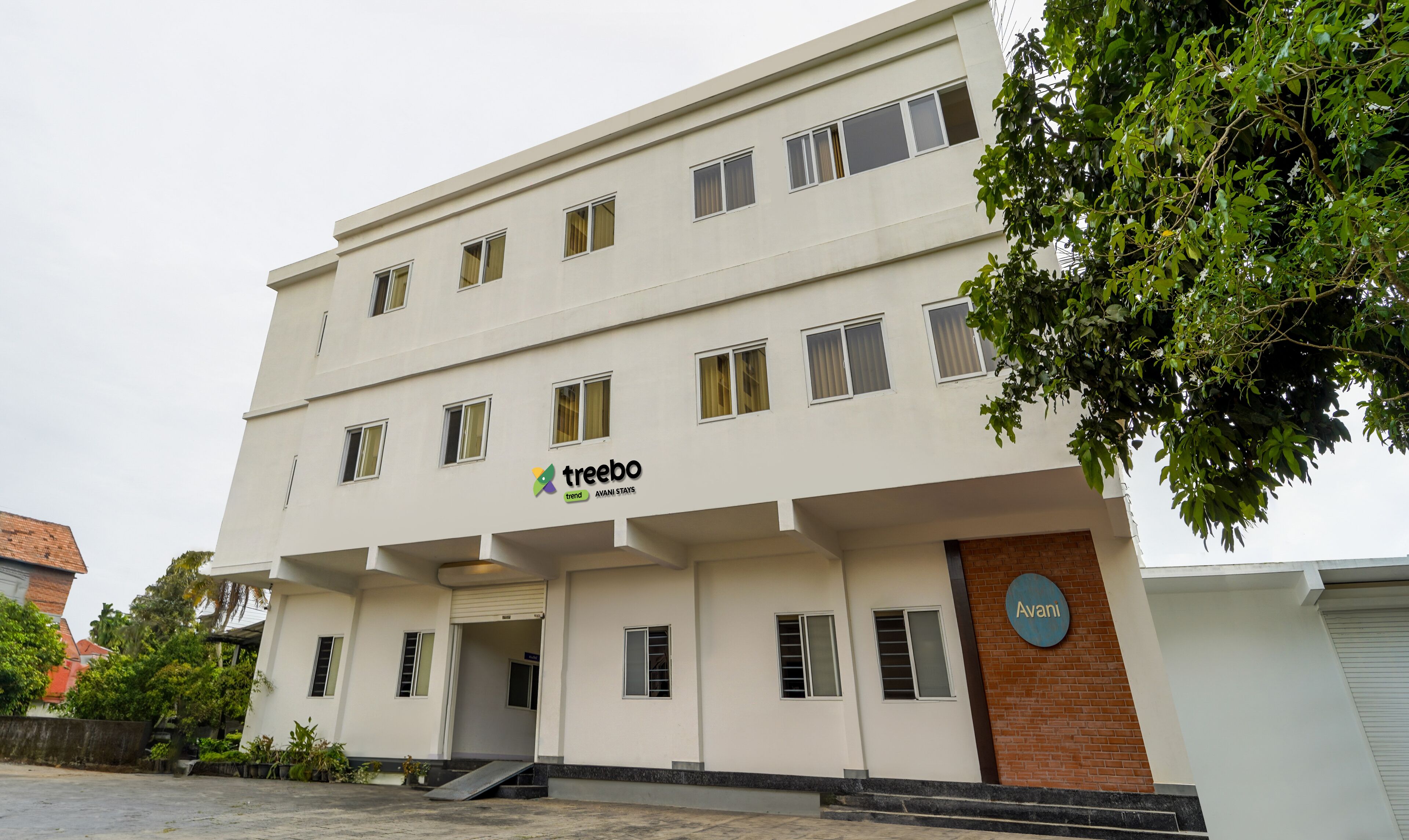 A multi-story building with a sign reading "treebo trend AVANI STAYS".