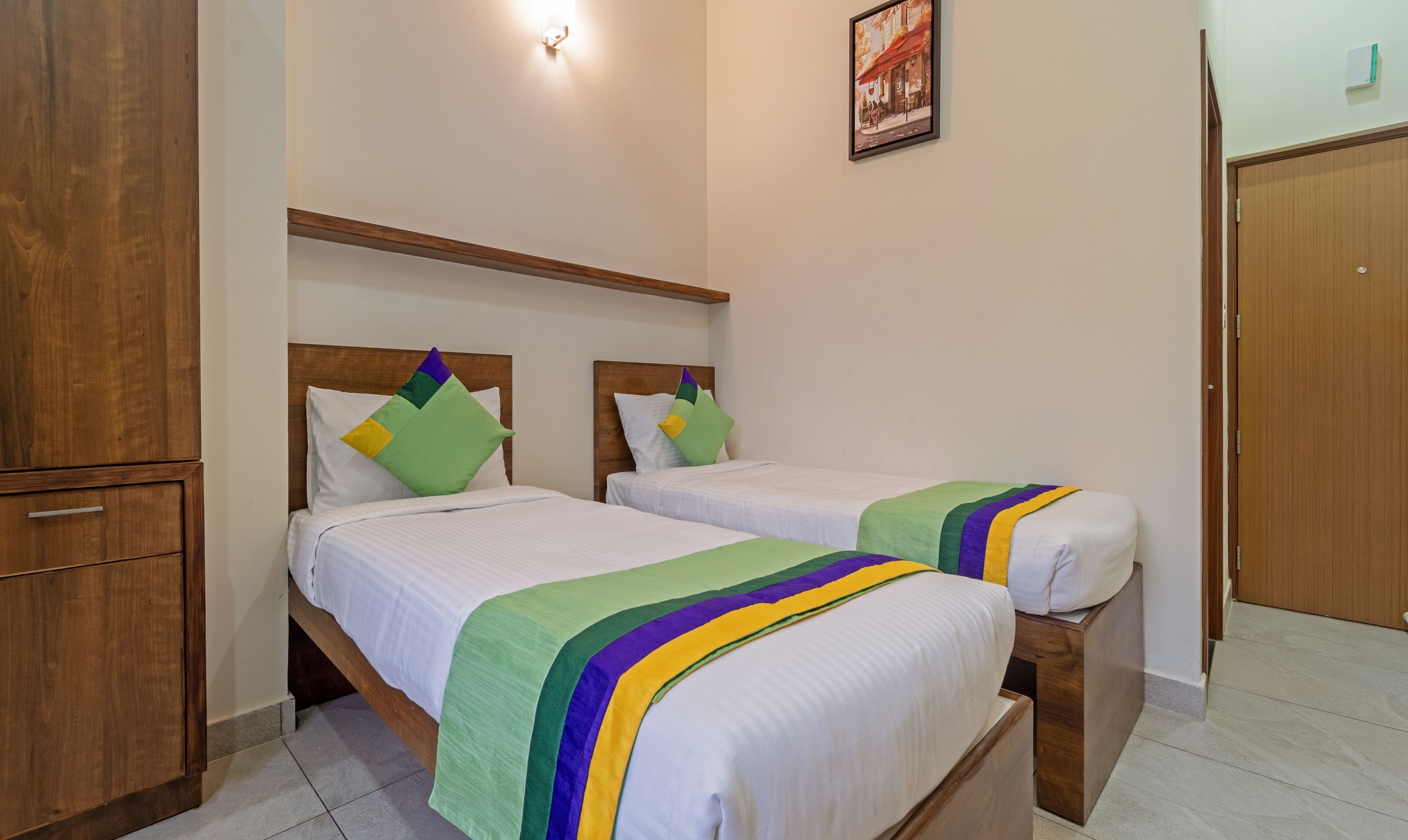 Ein Hotelzimmer mit zwei Betten, Holz-Kopfteilen, einem Kleiderschrank und einem gerahmten Bild an der Wand.