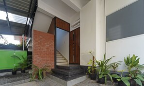 A modern entrance with a brick wall, a wooden door, and a staircase leading inside.