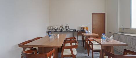 A dining area with wooden tables and chairs, a ceiling fan, and a kitchen area with appliances and a sink.