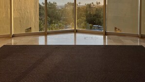 Una habitación con amplios ventanales del suelo al techo, piso de baldosas y vistas al mar y la vegetación.