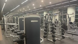 Un gimnasio con diferentes máquinas de ejercicio, espejos e iluminación superior.