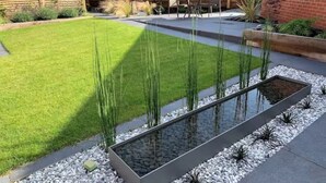 A backyard with a rectangular water feature, a well-maintained lawn, and a wooden fence. - Luxury detached house next to Gedling Country Park. Pet friendly! (Nottingham)