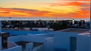 A rooftop terrace with a view of a cityscape at sunset.