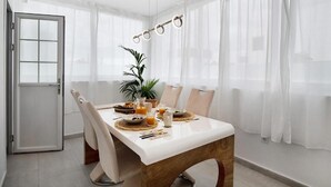 A dining area with a white table, beige chairs, and a potted plant.