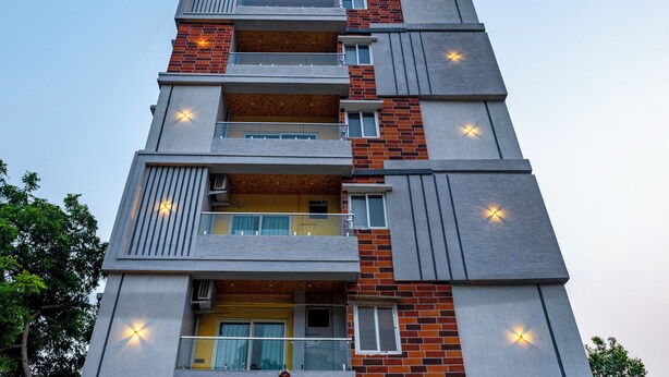 Un immeuble à plusieurs étages doté de balcons, de fenêtres et d’un éclairage extérieur.