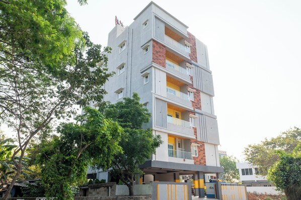 A multi-story residential building with balconies, a covered entrance, and surrounding greenery. - Treebo Breeze Way Rushikonda with Swimming Pool (Visakhapatnam)