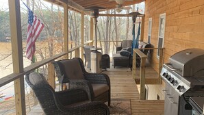 A covered porch with wicker furniture, a grill, and an American flag. - Waterfront Lake Gaston Retreat with beautiful views, Gameroom and covered deck. (Bracey)