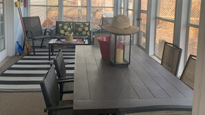 A sunroom with a large table, chairs, a ceiling fan, and large windows. - Waterfront Lake Gaston Retreat with beautiful views, Gameroom and covered deck. (Bracey)