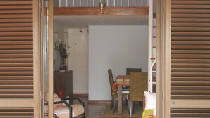 An open doorway leading to a dining area with a table, chairs, and a potted plant.