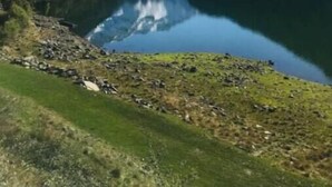 Un lac de montagne paisible, aux eaux limpides qui reflètent le paysage, entouré d’une végétation luxuriante et de sommets enneigés.
