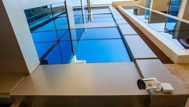Een modern interieur met een glanzende blauwe vloer, een beveiligingscamera en een kleine tafel.