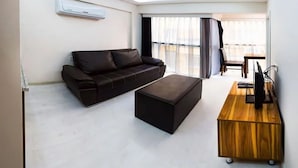 Een moderne woonkamer met een bank, voetenbankje en een houten bijzettafeltje.