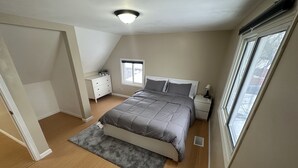 Quarto com cama, mesas de cabeceira, janela e luminária no teto.