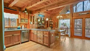 A spacious kitchen with wooden cabinets, a central island, and a dining area with chairs.