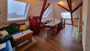 Acogedor dormitorio en el ático con vigas de madera, una mesa de comedor y un sofá.