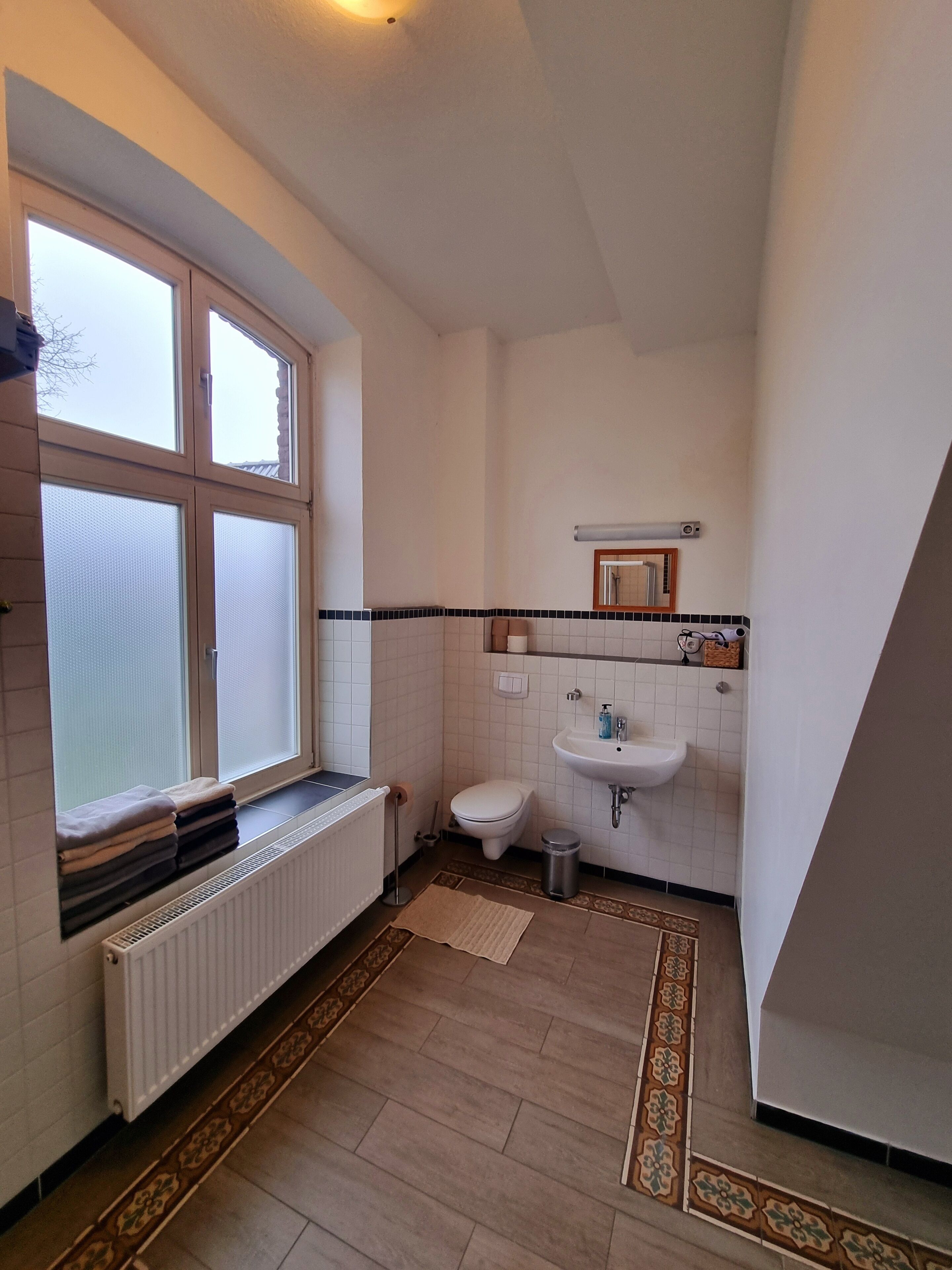 Ein kleines, sauberes Badezimmer mit Toilette, Waschbecken und Fenster.