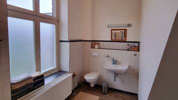 Ein kleines, sauberes Badezimmer mit Toilette, Waschbecken und Fenster.