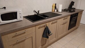 Uma cozinha equipada com micro-ondas, pia, fogão e forno.