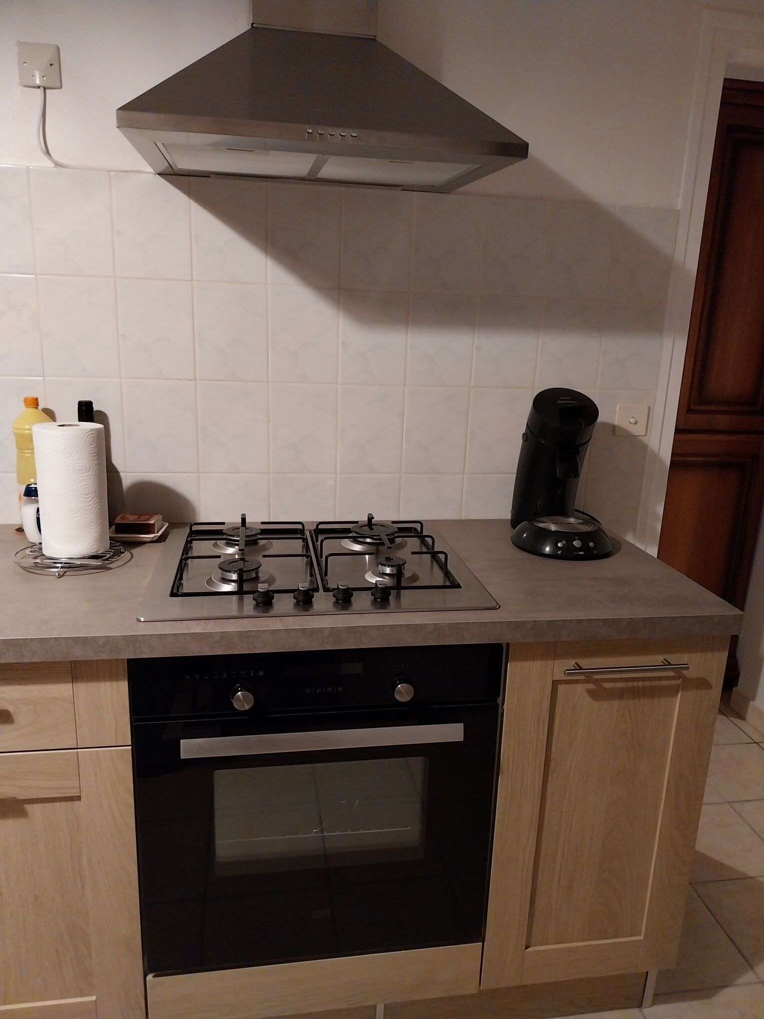 Eine Küche mit Gaskochfeld, Kaffeemaschine und Backofen.