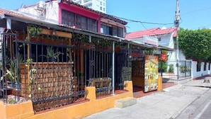 A building with a red roof, a metal fence, and a small outdoor seating area.