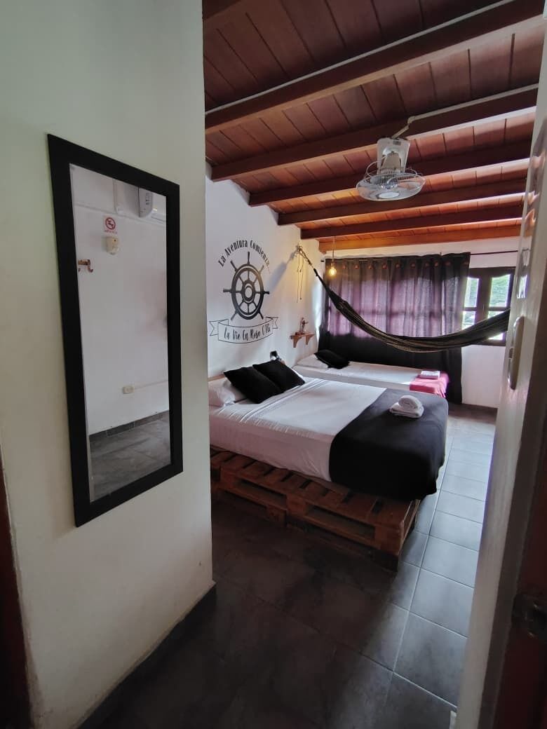 A room with two beds, a hammock, a ceiling fan, and a wall-mounted sign.
