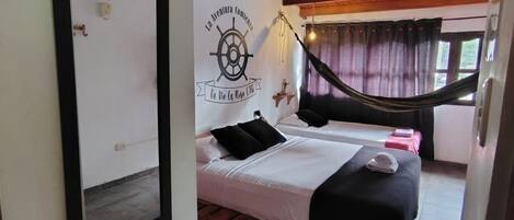 A room with two beds, a hammock, a ceiling fan, and a wall-mounted sign.