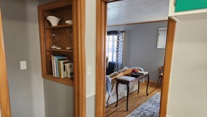 A room with a wooden bookshelf, a small table, a patterned rug, and a window with curtains. - Charming Family 1-level and pet-friendly Home (Austin)