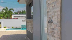 A modern building with a brick wall, a door, and a pool in the background.