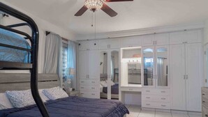 A bedroom with a bunk bed, a wardrobe, a desk, and a ceiling fan.