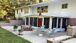A covered patio area with a table and chairs, a potted plant, and a brick wall.