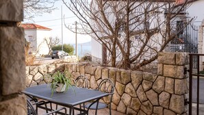 Un patio al aire libre con un muro de piedra, una mesa de metal y sillas.