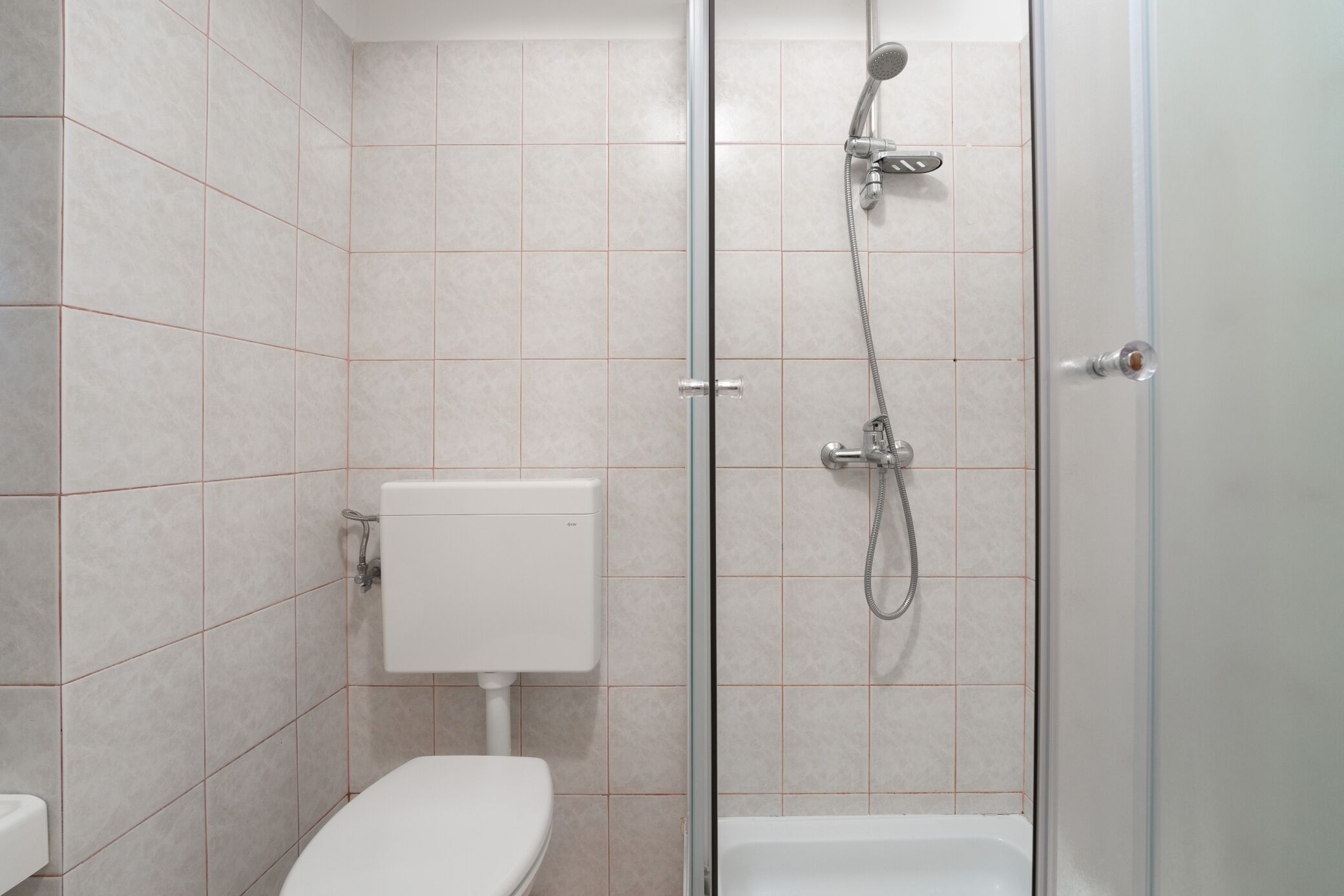 A modern bathroom with a glass-enclosed shower, a toilet, and a white sink.