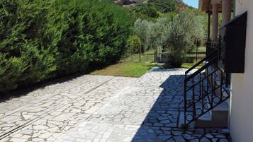 A stone-paved pathway leading to a building with a metal railing and a view of a mountain.