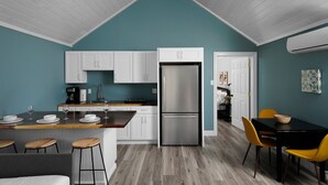A modern kitchen with white cabinets, a stainless steel refrigerator, and a teal accent wall. - River & Charm: 2 Homes, on 10 Acres Near Clayton (Clayton)