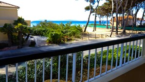 A balcony with a view of a beach, palm trees, and a clear sky.