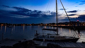 A dock with a sailboat, calm water, and a city skyline in the background.