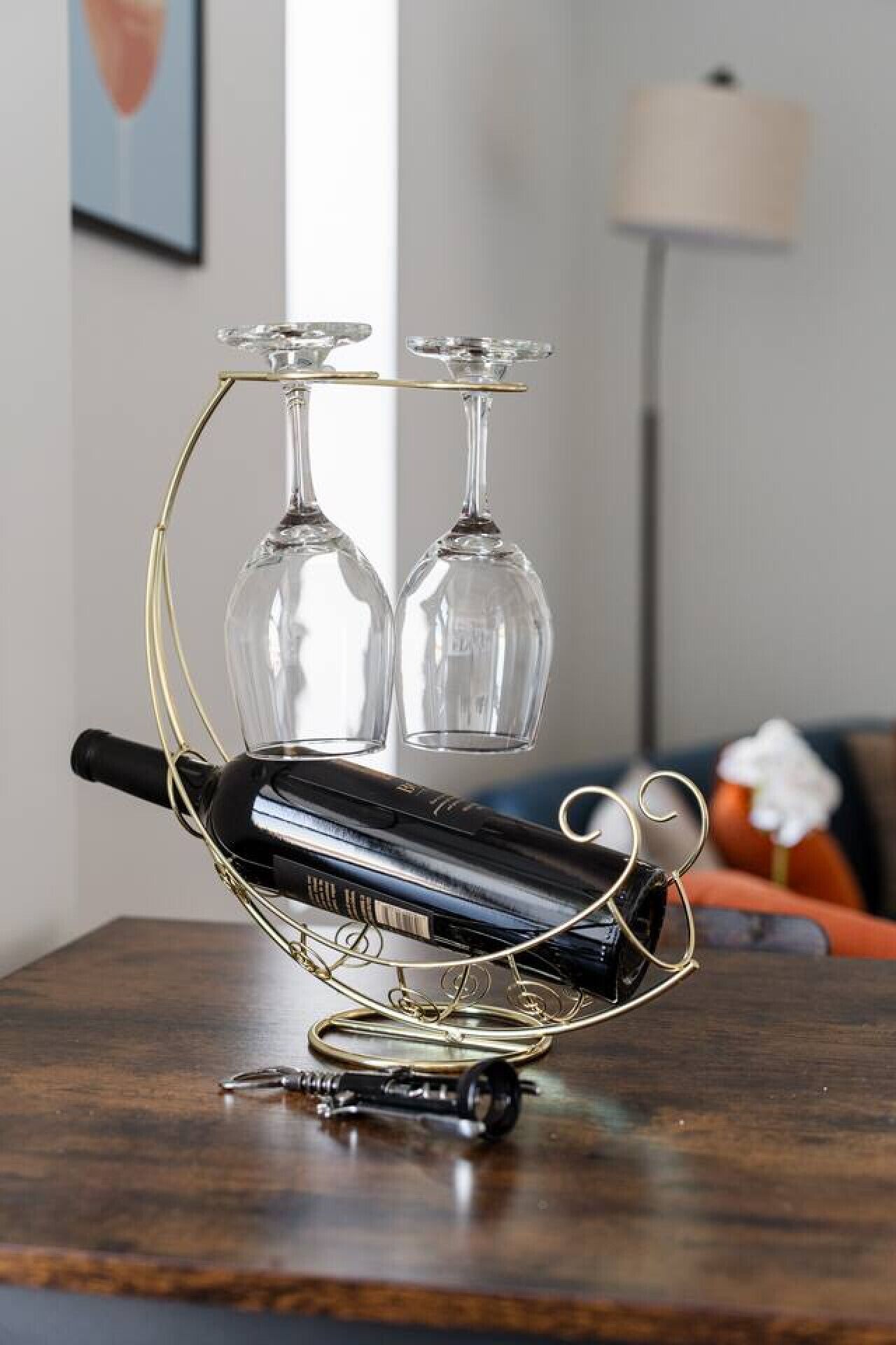 Une bouteille de vin est posée sur une table, et deux verres à vin sont fixés à son goulot.