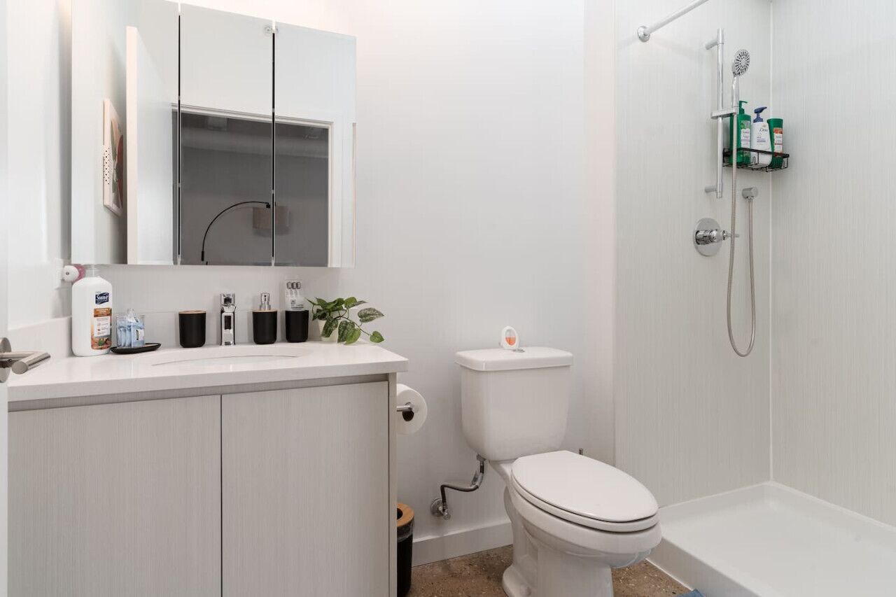 A modern bathroom with a toilet, sink, and shower.