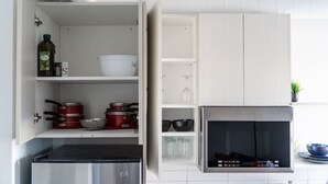 Una cocina con armarios blancos, estufa de acero inoxidable y microondas.