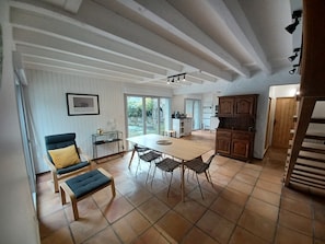 A spacious dining area with a large table and chairs, a kitchen with wooden cabinets, and a view of the outdoors through a sliding glass door. - Charmante Maison à Bourisp (Bourisp)