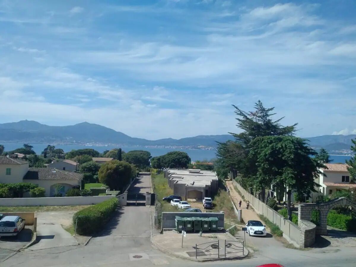 Zona residencial com casas, estacionamento e vista para o mar e montanhas.