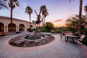 Relax in a serene, circular patio surrounded by lush greenery and a central fountain.
