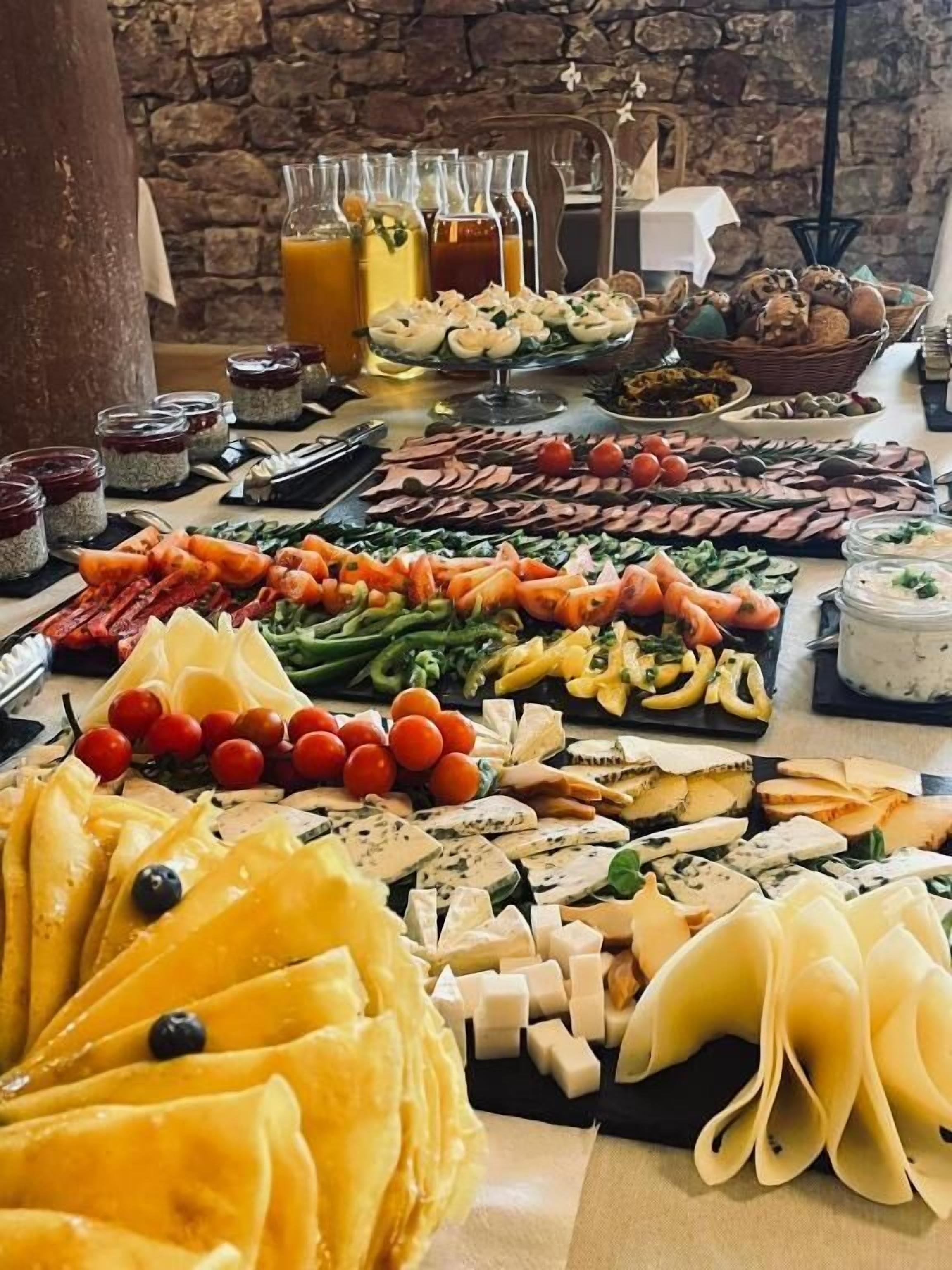 Un bufé con diferentes opciones de comida, incluyendo quesos, frutas, verduras y carnes.