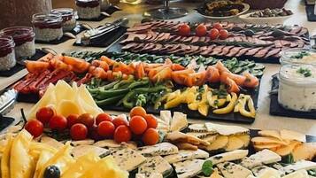 Un bufé con diferentes opciones de comida, incluyendo quesos, frutas, verduras y carnes.