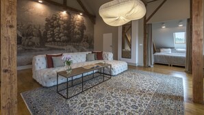 A cozy living room with a white tufted sofa, a patterned rug, and a large mural on the wall. - Zamek Sarny (Radkow)