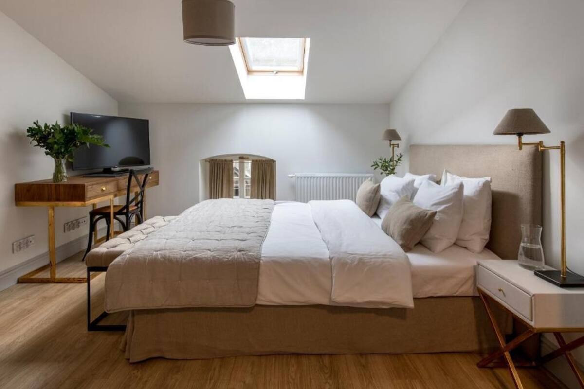 Et soveværelse med en seng, et skrivebord med fjernsyn, en lampe og en radiator.