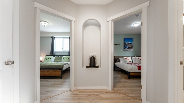 A hallway with two bedrooms, each with a bed and a window. - 5-Br/3-Ba | Private Pool & Hot Tub | Pool Table + Home Theatre (Hinton)